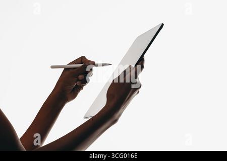 Nahaufnahme der Hände, die ein Tablet und einen Eingabestift halten, um Technologie und kreative Arbeitsabläufe hervorzuheben. Stockfoto