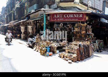 Interessante Szene vom Chor Bazaar, Antiquitätenläden in Mumbai in Indien, Mann auf einem Motorrad vorbei an Antiquitätenladen mit vielen historischen Gegenständen Stockfoto