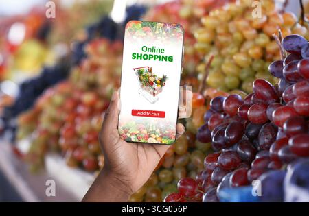 Lieferung von Lebensmitteln. Mann mit Handy-App, um Lebensmittel online zu bestellen, Nahaufnahme Stockfoto