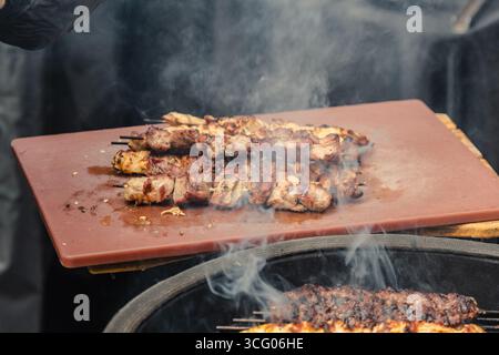 Saftiges Fleisch, das auf einem Brett gegrillt wird und beim Grillen verzehrt werden kann, wobei der Rauch steigt Stockfoto