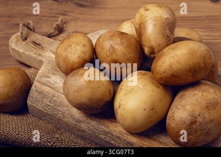 Rohe Kartoffeln, verstreut auf einem Schneidebrett, Nahaufnahme, keine Leute Stockfoto