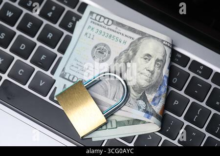 Cyber-Sicherheit. Vorhängeschloss aus Metall und Dollar auf Laptop, Blick von oben Stockfoto