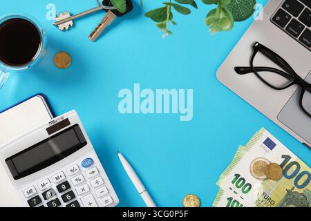 Taschenrechner, Euro-Banknoten, Münzen, Laptop, Kaffee, Schlüssel und Brille auf blauem Tisch mit Copyspace. Finanzierungsplanung und Geschäftsorganisation. Stockfoto