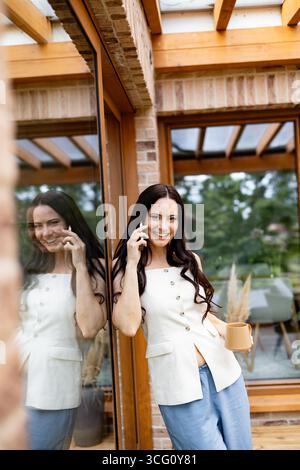 Lächelnde Frau, die draußen telefoniert. Stockfoto