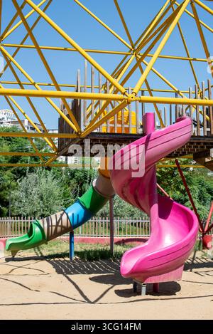 Farbenfrohe Spielplatzausrüstung mit Rutschen und Kletterstruktur unter klarem blauen Himmel Stockfoto