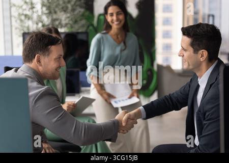 Zwei multiethnische, junge und reife männliche Profis schütteln die Hand Stockfoto