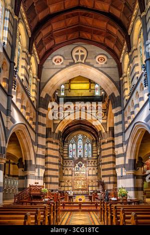 Innenansicht der anglikanischen St. Paul's Cathedral mit kunstvollen Bögen, Buntglasfenstern und Holzbänken in Melbourne, Australien. Stockfoto
