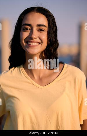 Junge Frau lächelt im Freien in urbaner Umgebung Stockfoto
