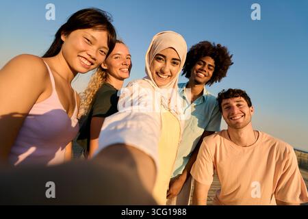 Glückliche Multi-ethnische Freunde, die Selfie bei Sonnenuntergang machen Stockfoto