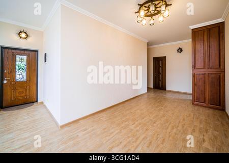 Ein großer leerer Raum mit einer Holztür und einem Fenster. Das Zimmer ist leer und hat ein einfaches Design Stockfoto