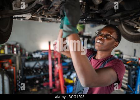 Junge afrikanische Mechanikerin repariert Auto in einer Werkstatt Stockfoto