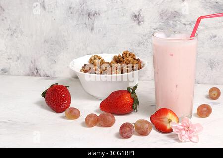 Nützliches Frühstück, Essen für Kinder, Erdbeerjoghurt, Smoothies und Müsli auf einem hellen Tisch. Das Konzept der gesunden und natürlichen Ernährung. Selektiv fo Stockfoto