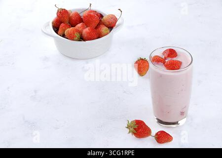 Nützliches Frühstück, Essen für Kinder, Erdbeerjoghurt, Smoothies und Müsli auf einem hellen Tisch. Das Konzept der gesunden und natürlichen Ernährung. Selektiv fo Stockfoto
