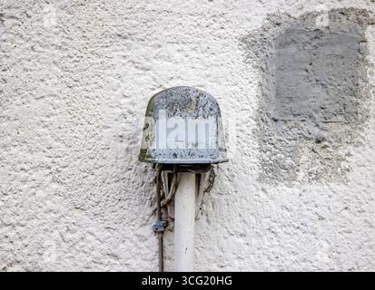 Nahaufnahme eines alten, verwitterten elektrischen Anschlusskastens für Telefon, der an einer weißen strukturierten Wand befestigt ist Stockfoto