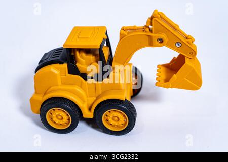 Gelber Spielzeugbagger mit schwarzen Rädern auf weißem Hintergrund Stockfoto