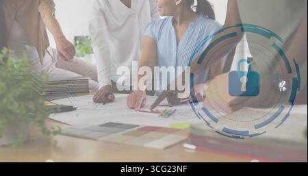 Schicke Designer, die Blusen tragen und im Büro Blaupausen lesen, mit Farbmustern und Schloss-Symbol Stockfoto