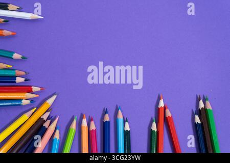 Leuchtende Buntstifte auf lila Hintergrund schaffen einen farbenfrohen Rahmen mit viel Platz für Text oder Designelemente Stockfoto