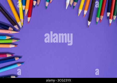 Farbenfrohe Bleistifte schaffen einen Rahmen auf violettem Hintergrund und lassen viel Platz für Text oder Designelemente Stockfoto