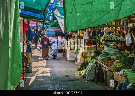 Balikpapan, Indonesien – 22. Juli 2025. Zwei Frauen laufen durch einen farbenfrohen traditionellen Markt mit frischem Gemüse und täglichen Vorräten unter PA Stockfoto