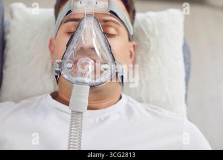 Porträt eines jungen Mannes, der zu Hause mit einer Sauerstoffmaske auf einer Couch liegt. Stockfoto