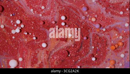 Tintenpartikel. Lackwasser. Defokussierte rote lila orange bunte schimmernde Öl-weiße Tropfen glitzernde Glitzerflüssigkeit, die auf abstraktem Hintergrund schwimmt. Stockfoto