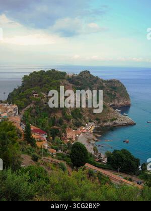 Regnerische Aussicht auf die Küste von Taormina mit dramatischem Kontrast von wolkenlosem, dunklem Meer auf der linken Seite und hellem Himmel auf der rechten Seite, Hügellandhäuser und Strand sichtbar Stockfoto