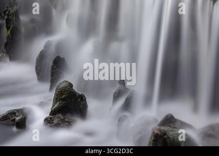 Lange Belichtungsdauer Wasserfall Nahaufnahme mit seidenem Wasser über moosigen Felsen, nebeliges Licht, nasser Steinstruktur, langsamer Verschluss, Naturdetails für den Hintergrund Stockfoto