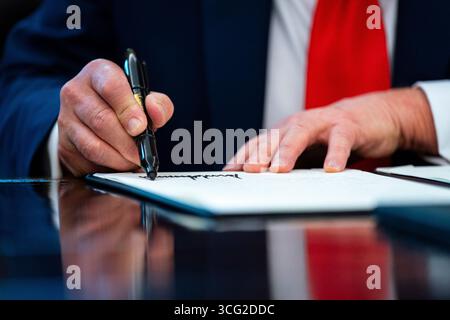 Washington, DC, USA. August 2025. US-Präsident Donald J Trump unterzeichnet am Montag, den 25. August, eine Anordnung im Oval Office des Weißen Hauses in Washington, DC, USA. 2025. Trump unterzeichnet am Montag zwei Befehle, die darauf abzielen, die bargeldlose Kaution in Washington und im ganzen Land zu beenden. dies markiert den jüngsten Schritt in der Agenda der Regierung, gegen Verbrechen vorzugehen. Quelle: Al Drago/Pool über CNP/dpa/Alamy Live News Stockfoto