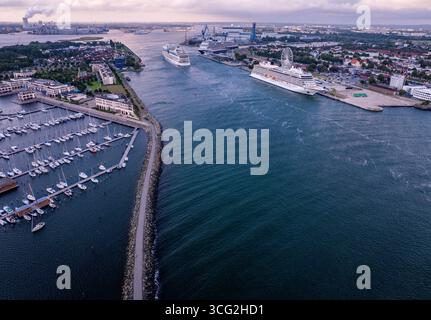 Rostock, Deutschland. August 2025. Das Kreuzfahrtschiff 'AIDAmar' passiert am Morgen die Schiffe 'Viking Sky' (rechts) und 'Rotterdam' (hinten) auf dem Meereskanal. Die Segelboote liegen morgens im Jachthafen des Hotelkomplexes hohe Düne. Insgesamt drei Kreuzfahrtschiffe mit insgesamt 12.000 Gästen legen während des zweiten Triple-Call bis zum Abend am Kreuzfahrtterminal in Warnemünde an. Quelle: Jens Büttner/dpa/Alamy Live News Stockfoto