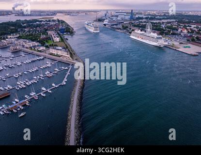 Rostock, Deutschland. August 2025. Das Kreuzfahrtschiff 'AIDAmar' passiert am Morgen die Schiffe 'Viking Sky' (rechts) und 'Rotterdam' (hinten) auf dem Meereskanal. Die Segelboote liegen morgens im Jachthafen des Hotelkomplexes hohe Düne. Insgesamt drei Kreuzfahrtschiffe mit insgesamt 12.000 Gästen legen während des zweiten Triple-Call bis zum Abend am Kreuzfahrtterminal in Warnemünde an. Quelle: Jens Büttner/dpa/Alamy Live News Stockfoto