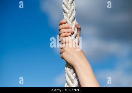 Nahaufnahme von Kinderhänden, die im Freien Sportseil mit klarem Himmel greifen, Konzept von Kraft, Spiel und Aktivität Stockfoto