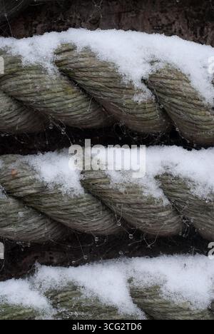 Seilstränge sind in kalter Umgebung mit Schnee bedeckt und zeigen komplizierte Texturen und vereiste Details in den Fasern. Stockfoto