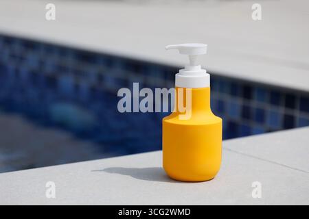 Gelbe Spenderflasche für den Außenbereich. Swimmingpool und Kosmetik, Sonnenschutz. Reisekonzept, Kosmetikkonzept, Werbung Stockfoto