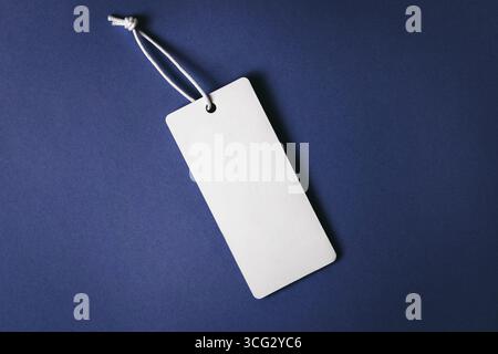 Weißes Etikett auf dunkelblauem Hintergrund. Modellerstellung, Kopierbereich für Text, Draufsicht Stockfoto