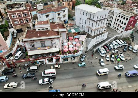 Antananarivo (TNR), Madagaskar – 11.2023: Aus der Vogelperspektive auf die Dachschirme der Planète Terrasse über der Transitstraße Ambohijatovo mit Taxi und Motos Stockfoto