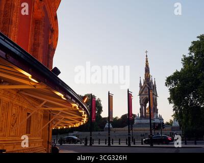 Albert Memorial rechts an einem Sommerabend in London, wenn Autos vorbeifahren und ein Teil der Royal Albert Hall links ist . August 2025 Stockfoto