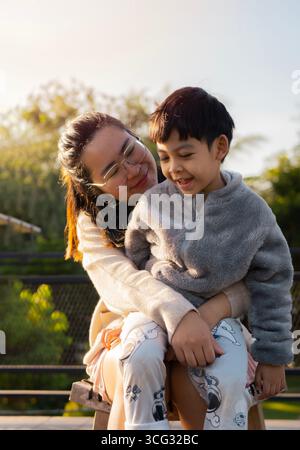 Frau und ihr Sohn umarmen sich morgens im Freien an einem Sommertag. Glücklicher, authentischer Familienstil. Stockfoto