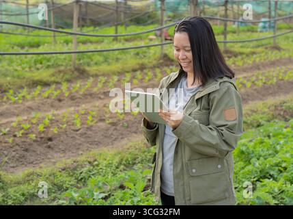 Seitenporträt eines lächelnden Gartenarbeiters mit digitalem Tablet im Gewächshaus. Sapce kopieren. Stockfoto