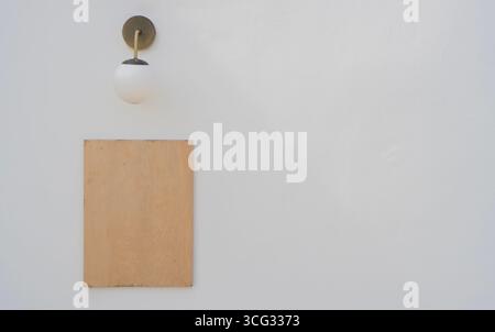 Leerer Holzrahmen mit runder Lampe auf leerem auf sauberem weißem Zementhintergrund. Kopierbereich. Stockfoto