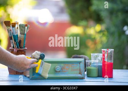 Holzmöbel mit Kreidemalerei aus menschlicher Hand. Alte Holzmöbel werden mit brandneuer, farbenfroher Kreidefarbe erneuert. Die Innendekoration wird neu gestaltet Stockfoto