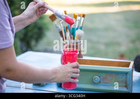 Holzmöbel mit Kreidemalerei aus menschlicher Hand. Alte Holzmöbel werden mit brandneuer, farbenfroher Kreidefarbe erneuert. Die Innendekoration wird neu gestaltet Stockfoto