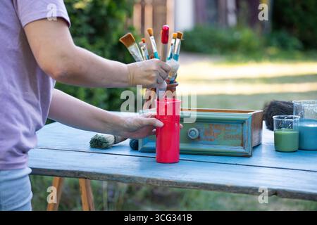 Holzmöbel mit Kreidemalerei aus menschlicher Hand. Alte Holzmöbel werden mit brandneuer, farbenfroher Kreidefarbe erneuert. Die Innendekoration wird neu gestaltet Stockfoto