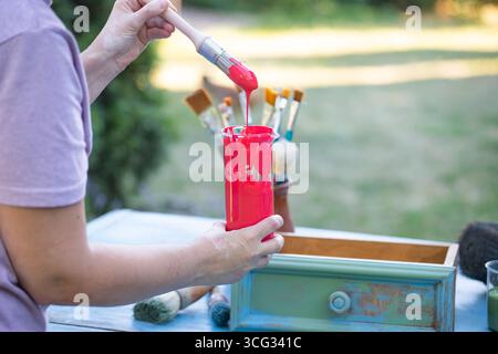 Holzmöbel mit Kreidemalerei aus menschlicher Hand. Alte Holzmöbel werden mit brandneuer, farbenfroher Kreidefarbe erneuert. Die Innendekoration wird neu gestaltet Stockfoto