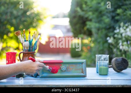 Holzmöbel mit Kreidemalerei aus menschlicher Hand. Alte Holzmöbel werden mit brandneuer, farbenfroher Kreidefarbe erneuert. Die Innendekoration wird neu gestaltet Stockfoto