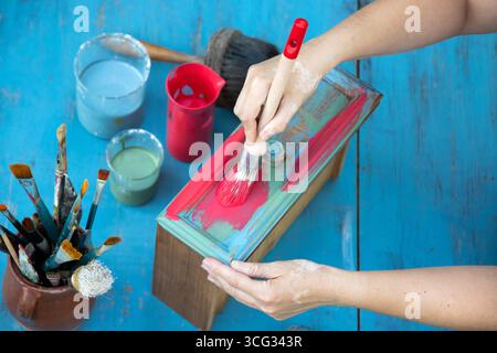 Holzmöbel mit Kreidemalerei aus menschlicher Hand. Alte Holzmöbel werden mit brandneuer, farbenfroher Kreidefarbe erneuert. Die Innendekoration wird neu gestaltet Stockfoto