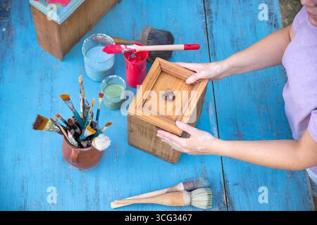 Holzmöbel mit Kreidemalerei aus menschlicher Hand. Alte Holzmöbel werden mit brandneuer, farbenfroher Kreidefarbe erneuert. Die Innendekoration wird neu gestaltet Stockfoto