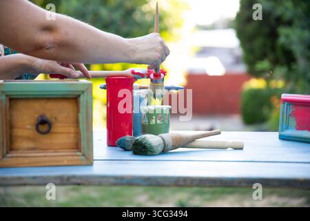 Holzmöbel mit Kreidemalerei aus menschlicher Hand. Alte Holzmöbel werden mit brandneuer, farbenfroher Kreidefarbe erneuert. Die Innendekoration wird neu gestaltet Stockfoto