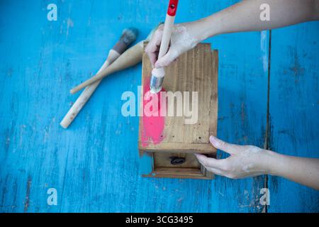 Holzmöbel mit Kreidemalerei aus menschlicher Hand. Alte Holzmöbel werden mit brandneuer, farbenfroher Kreidefarbe erneuert. Die Innendekoration wird neu gestaltet Stockfoto