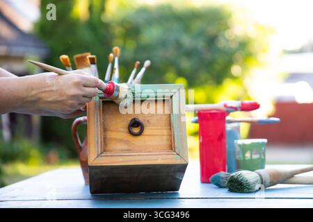 Holzmöbel mit Kreidemalerei aus menschlicher Hand. Alte Holzmöbel werden mit brandneuer, farbenfroher Kreidefarbe erneuert. Die Innendekoration wird neu gestaltet Stockfoto