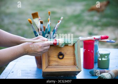 Holzmöbel mit Kreidemalerei aus menschlicher Hand. Alte Holzmöbel werden mit brandneuer, farbenfroher Kreidefarbe erneuert. Die Innendekoration wird neu gestaltet Stockfoto